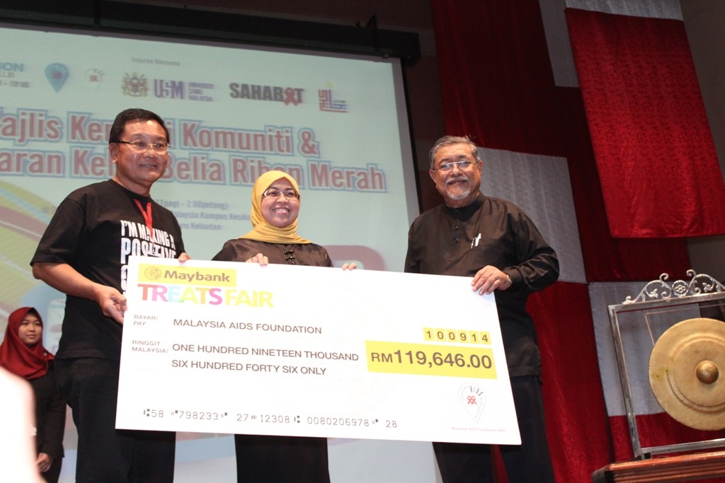 ​Naib Presiden Eksekutif, Ketua Pemasaran Kad Malaysia, Maybank Berhad Pn. Marlin Tan Sri Ahmad Nordin (tengah) menyampaikan cek sumbangan bernilai RM119,646 kepada Setiausaha Kehormat Yayasan AIDS Malaysia En. Hisham Hussein (kiri) dan disaksikan oleh Presiden SAHABAT Tan Sri Mohd Zaman Khan Rahim Khan (kanan).