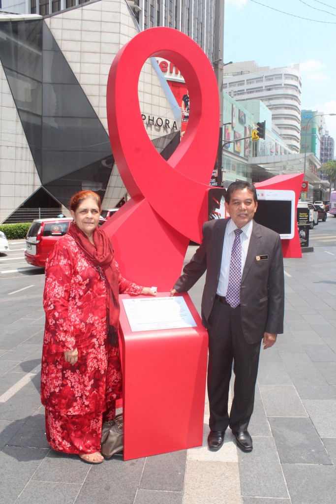 Datuk Dr. Raj Karim, President, Malaysian AIDS Council (left) and Dato’ Seri Dr. Hilmi Bin Haji Yahaya, Deputy Minister of Health Malaysia at the giant red ribbon installation near the main entrance of Pavilion Kuala Lumpur commemorating the Ending AIDS Begins Now campaign. The red ribbon is a global symbol of awareness and concern for people living with or affected by HIV & AIDS, as well as the mark of solidarity in the fight against HIV & AIDS related stigma and discrimination. Photo © 2016 Malaysian AIDS Council & Malaysian AIDS Foundation.